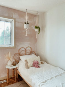 Children's room with pink wallpaper feature wall and macrame headboard.